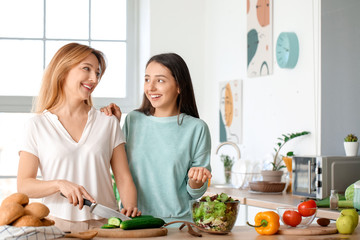 Mature woman with her adult daughter cooking together at home