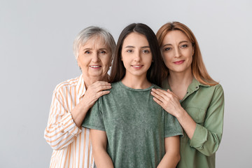 Portrait of mature woman with her adult daughter and mother on grey background