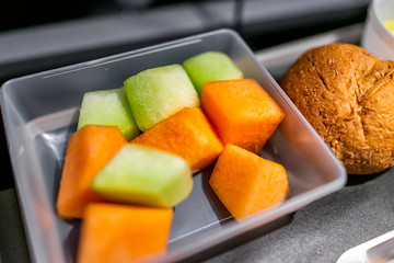 Healthy vegan vegetarian food vgml fruit snack meal on airplane flight with dessert sliced orange melon fruit and bread