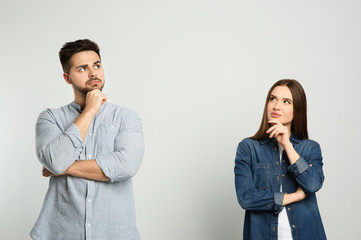 Pensive couple on light background. Thinking about answer for question - obrazy, fototapety, plakaty