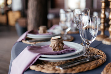 Festive table setting. Glass for the wine, white round plates and cutlery at a festive table, close-up. Side view