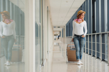 A woman with hand luggage walking in airport terminal