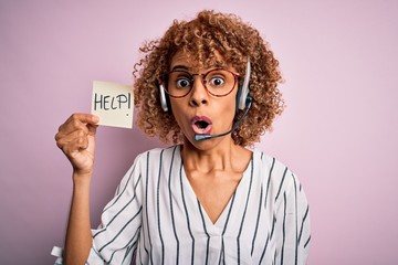 African american call center agent woman using headset holding paper with help message scared in...