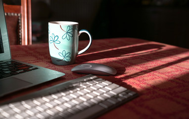 Laptop with wireless keyboard and mouse and coffee in cup. Work from home.