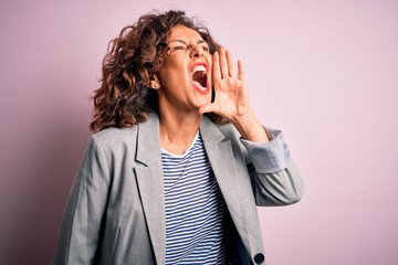 Middle age beautiful businesswoman wearing elegant jacket over isolated pink background shouting and screaming loud to side with hand on mouth. Communication concept.