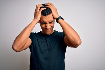 Young handsome african american man wearing casual t-shirt standing over white background suffering from headache desperate and stressed because pain and migraine. Hands on head.
