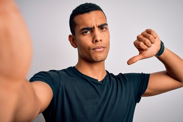 Young handsome african american man wearing casual t-shirt making selfie by camera with angry face,...