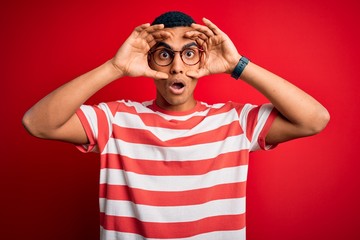 Young handsome african american man wearing casual striped t-shirt and glasses Trying to open eyes...