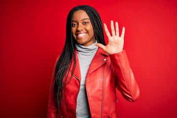 Young african american woman wearing cool fashion leather jacket over red isolated background showing and pointing up with fingers number five while smiling confident and happy.