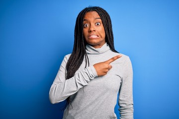Young african american woman standing wearing casual turtleneck over blue isolated background...