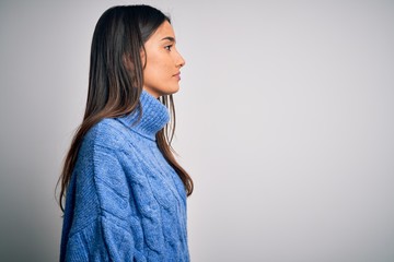 Young beautiful brunette woman wearing casual turtleneck sweater over white background looking to...