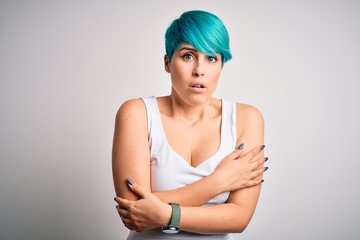 Young beautiful woman with blue fashion hair wearing casual t-shirt over white background shaking...