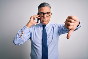 Middle age handsome grey-haired business man having conversation talking on the smartphone with angry face, negative sign showing dislike with thumbs down, rejection concept
