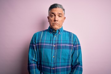 Middle age handsome grey-haired man wearing casual shirt over isolated pink background depressed and worry for distress, crying angry and afraid. Sad expression.