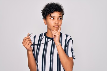 Young beautiful african american afro referee woman wearing striped uniform using whistle serious...