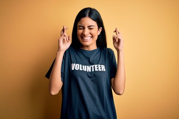Young beautiful hispanic woman wearing volunteer t-shirt as social charity moral gesturing finger...