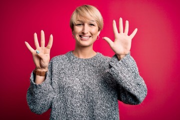 Young blonde woman with modern short hair wearing casual sweater over pink background showing and...