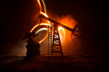 Oil pump and oil refining factory at night with fog and backlight. Energy industrial concept. Selective focus.