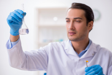 Young male lab assistant in drug synthesis concept