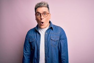 Fototapeta premium Young handsome modern man wearing glasses and denim jacket over pink isolated background afraid and shocked with surprise expression, fear and excited face.