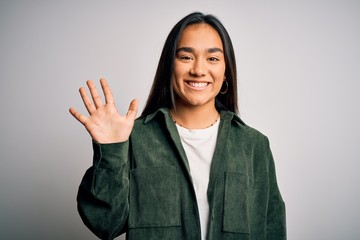 Young beautiful asian woman wearing casual shirt standing over isolated white background showing and pointing up with fingers number five while smiling confident and happy.