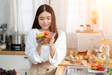 Asian Young Woman Cookingc Salad in the Kitchen.