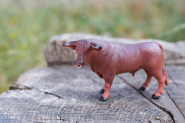 A brown bull model stands on a stump. Plastic toy bull. Symbol of the year 2021