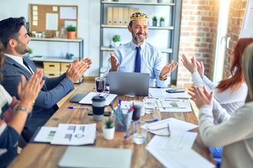 Group of business workers smiling happy and confident. Working together with smile on face applauding one of them wearing king crown at the office