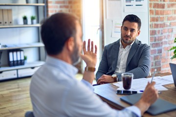 Two handsome businessmen sitting and speaking relaxed at the office
