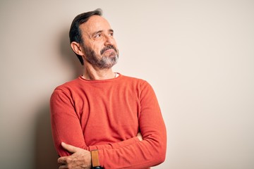 Fototapeta premium Middle age hoary man wearing casual orange sweater standing over isolated white background looking to the side with arms crossed convinced and confident
