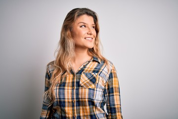 Fototapeta premium Young beautiful blonde woman wearing casual shirt standing over isolated white background looking away to side with smile on face, natural expression. Laughing confident.