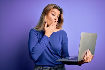 Young beautiful blonde woman working using laptop over isolated purple background cover mouth with hand shocked with shame for mistake, expression of fear, scared in silence, secret concept