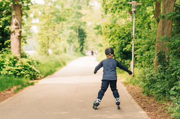 Active little boy skating in summer park, healthy lifestyle for children, back view