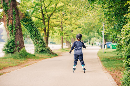 Active little boy skating in summer park, healthy lifestyle for children, back view