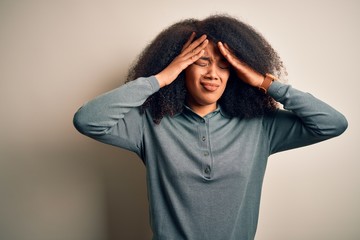 Young beautiful african american woman with afro hair standing over isolated background suffering from headache desperate and stressed because pain and migraine. Hands on head.