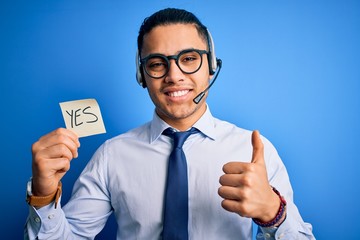Young brazilian call center agent man holding reminder paper with yes message happy with big smile...