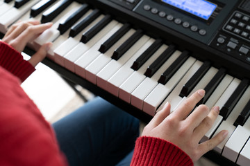 Fototapeta premium Little girl hands on piano keyboard playing song, winter theme