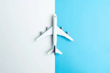 Poster Im Rahmen Flat lay miniature airplane model isolated on white and blue background © Kenishirotie