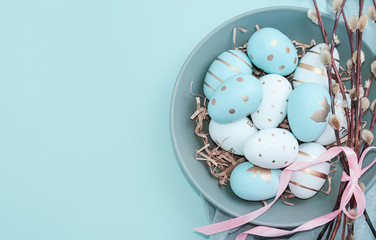 Easter background with Easter eggs in bird nest on blue background