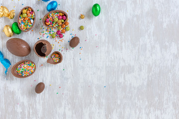 Fototapeta na wymiar Chocolate easter eggs with sprinkles and other candy on white wooden table top