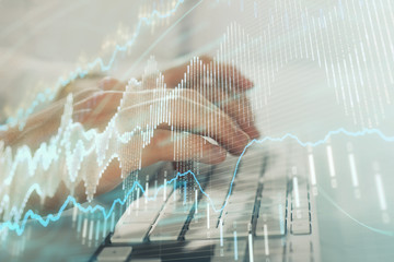 Double exposure of graph with man typing on computer in office on background. Concept of hard work. Closeup.