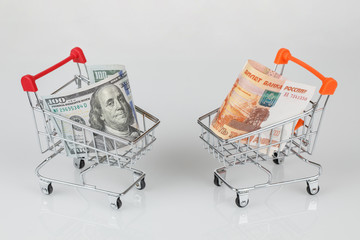 Mini shopping carts with dollar and rouble banknotes, money concept