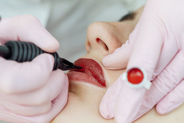 Woman having permanent makeup on lips in beauty salon