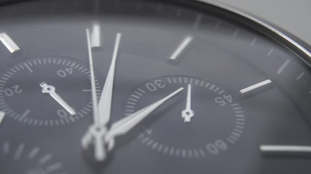 Silver hands of a dark wristwatch on a black dial. Macro shot. Idea flow of time
