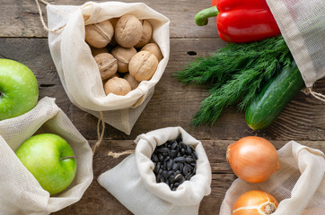 Various foods in reusable bags on a wooden background