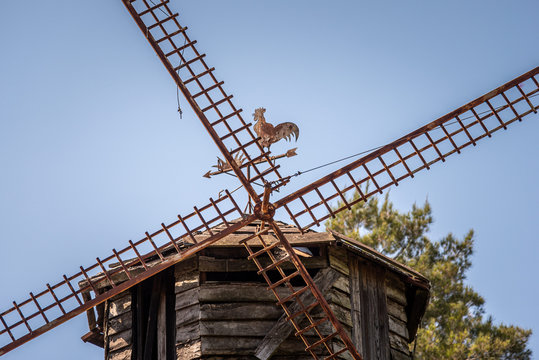 Close up of an old rusty and grungy traditional wooden dutch windmill with a rooster shaped vane