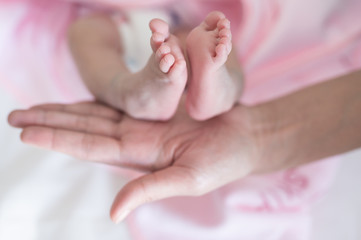 Fototapeta na wymiar Baby foots on mother hand.Newborn baby feet and relax action with pink blanket.Happy time family concept.