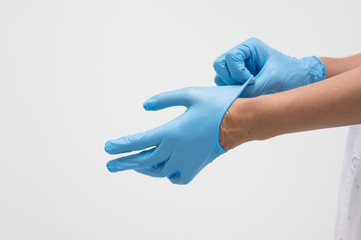 Woman doctor putting blue latex medical gloves on white background.Surgeon wearing gloves before surgery at operating room.Risk and infection control concept.