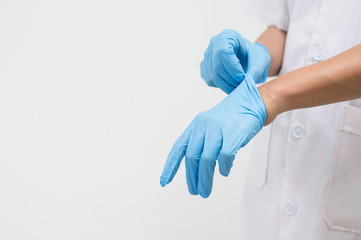 Woman doctor putting blue latex medical gloves on white background.Surgeon wearing gloves before...