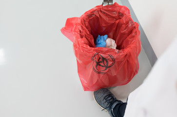 Close up scientist foot and red bag with bioharzard sign.Worker foot pushing red garbage bag.Maid...